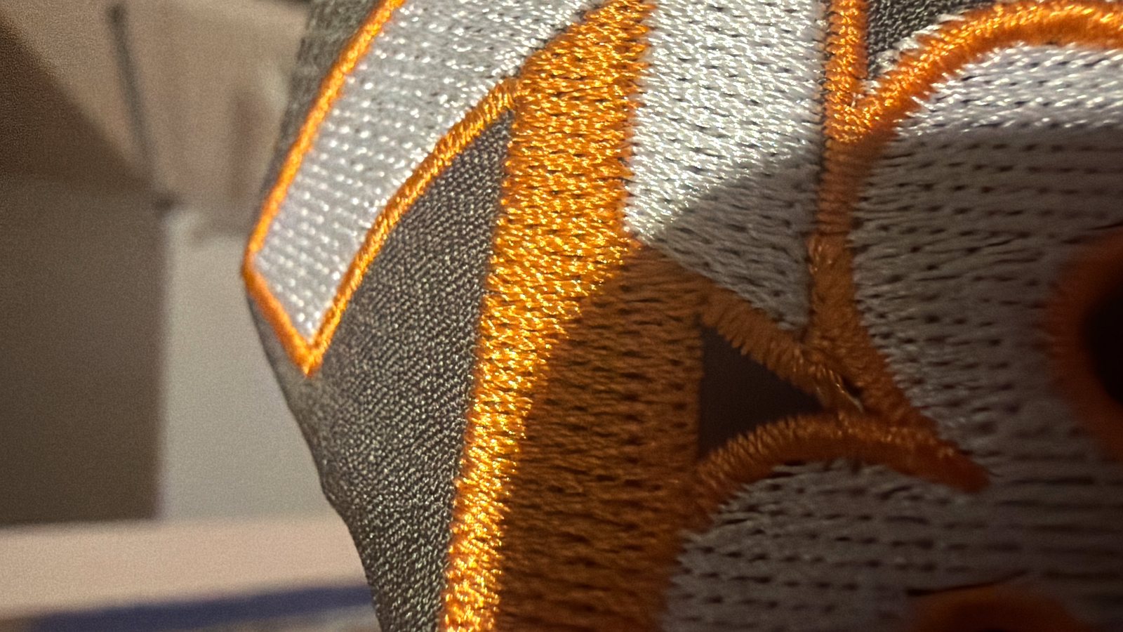 Detalle macro de un logo bordado: se aprecian las puntadas de hilo sobre la tela
